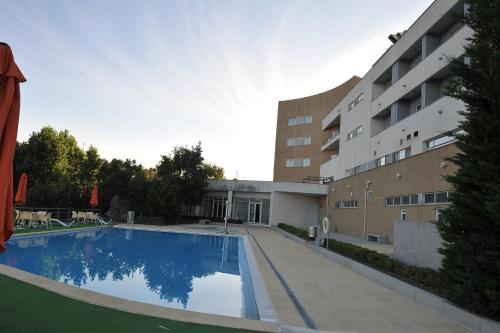 uma grande piscina em frente a um edifcio em Hotel Lusitania Congress & Spa na Guarda