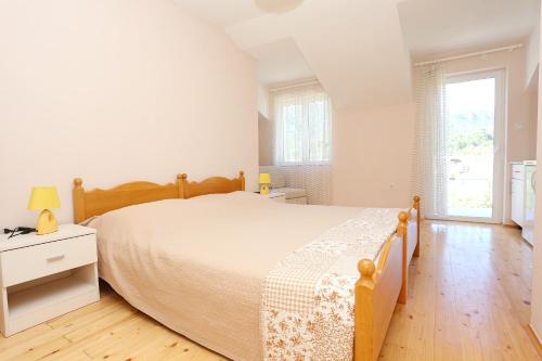 a white bedroom with a bed and a wooden floor at Apartments and rooms by the sea Zuljana, Peljesac - 4576 in Žuljana