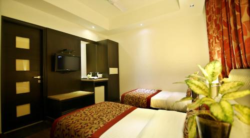 a hotel room with two beds and a tv at Hotel The Prime Balaji Deluxe, City Centre, With Free Airport Pickup in New Delhi