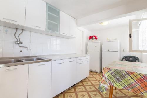 a white kitchen with a sink and a refrigerator at Seaside holiday house Cove Zarace - Gdinj, Hvar - 4603 in Gdinj