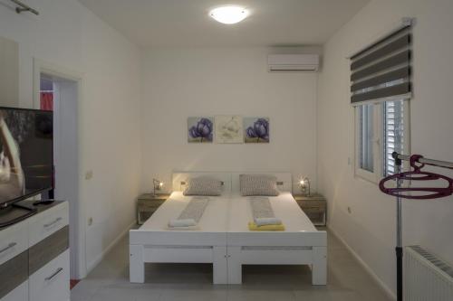 Dieses weiße Zimmer verfügt über ein Bett und einen TV. in der Unterkunft Studio Zuljana 4573b in Žuljana
