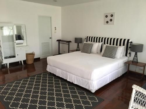 a bedroom with a large white bed and a mirror at Aster 9 House in Bangkok