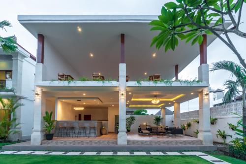 a large white house with palm trees at Puri Uma Ratu by RPM in Seminyak