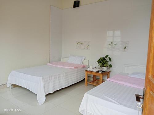 two beds in a white room with pink sheets at Hoa Lan Hotel in Bak Kan