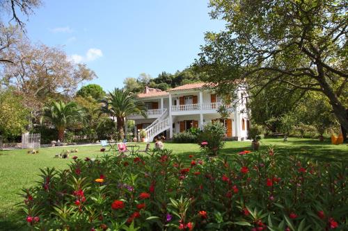 Une grande maison blanche avec des fleurs dans la cour dans l'établissement Villa Karidia, à Asprogerakata