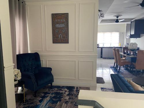 a living room with a blue chair and a table at Cheerfull3 bedroom townhouse Terrace in Kampung Dengkil