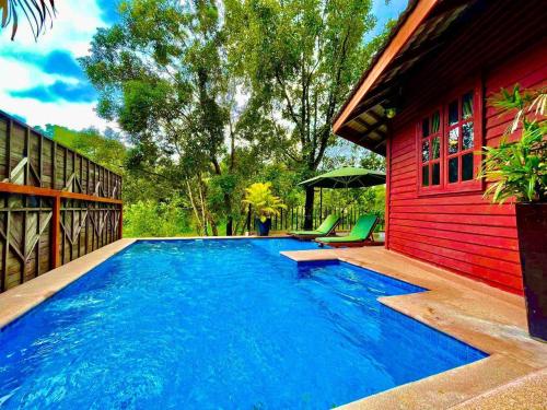 a swimming pool next to a red house at Kirirom Hillside Resort in Kampong Speu