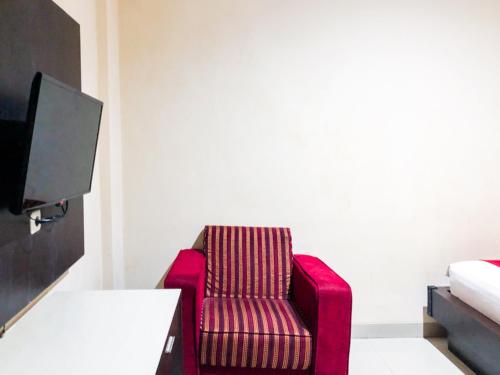 una silla roja en una habitación con TV en RedDoorz At Hotel Gajah Mada Palu, en Palu