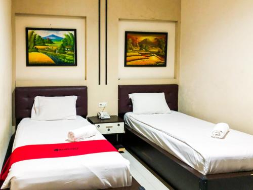 dwa łóżka w pokoju z obrazami na ścianie w obiekcie RedDoorz At Hotel Gajah Mada Palu w mieście Palu
