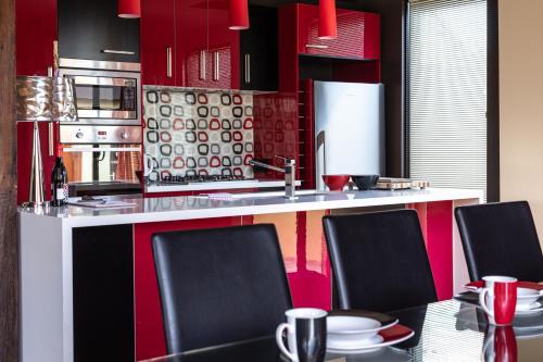a kitchen with red and black cabinets and a table with chairs at Corinda Contemporary in Hobart