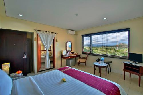 a bedroom with a bed and a desk and a television at The Jayakarta Suites Komodo Flores in Labuan Bajo