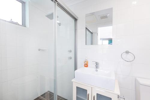a white bathroom with a sink and a shower at Shores Unit 201 in Forster