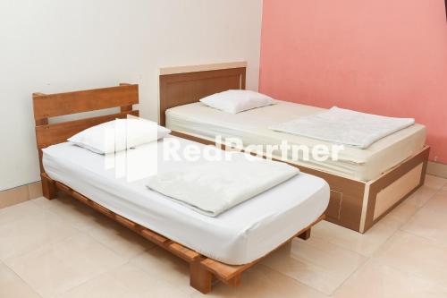 - 2 lits jumeaux dans une chambre aux murs blancs dans l'établissement Homestay Rumah Citra Indah Syariah Mitra RedDoorz, à Bukittinggi