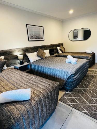 Una habitación de hotel con dos camas y un espejo. en Y Motels Gympie, en Gympie