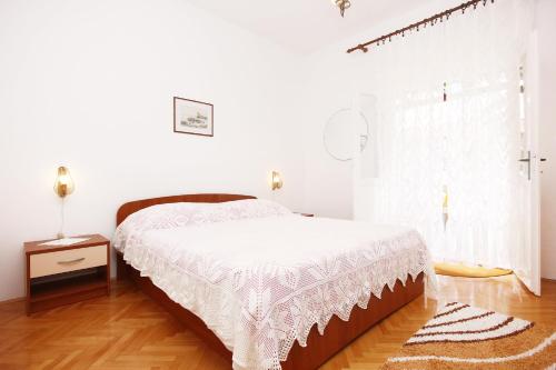 een witte slaapkamer met een bed en een raam bij Apartments by the sea Orebic, Peljesac - 4525 in Orebić