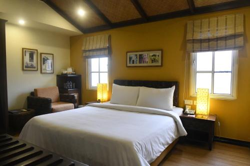 a bedroom with a bed and a chair and windows at The Richmond in Pondicherry