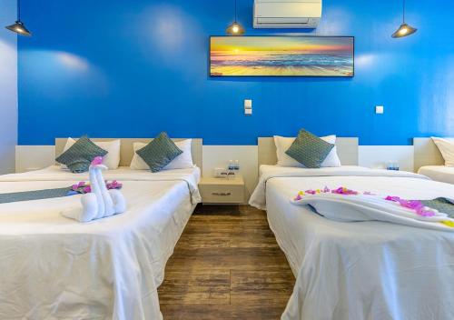 two beds in a room with a blue wall at Sara Resort in Koh Rong Sanloem