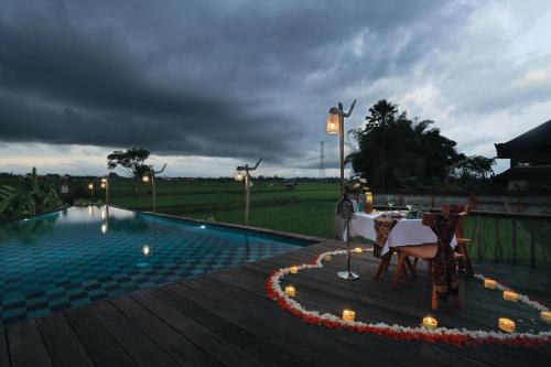 a pool with a table and chairs on a wooden deck at Maha Shanti Ubud Villa in Ubud