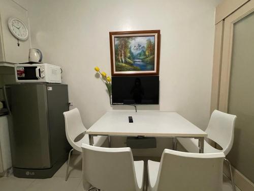 a dining room with a table and white chairs at Premiere Haven MOA Staycation in Manila