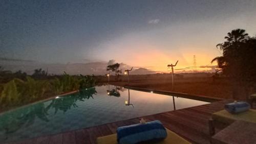 een zwembad met een zonsondergang op de achtergrond bij Maha Shanti Ubud Villa in Ubud