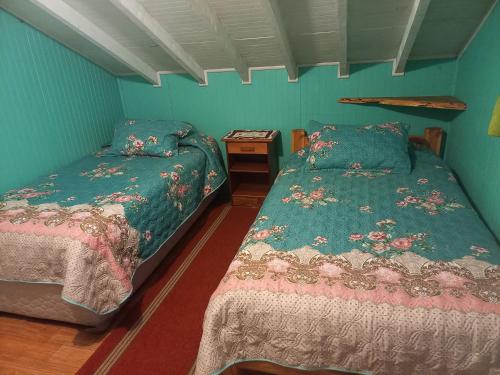 2 camas en una habitación con paredes azules en Cabañas Jade, en Cochamó