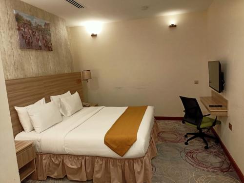 a hotel room with a large bed and a desk at Grand Tourist Hotel in Muscat