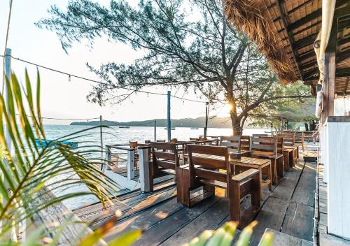 une rangée de bancs en bois assis sur une terrasse près de l'eau dans l'établissement Sara Resort, à Koh Rong Sanloem