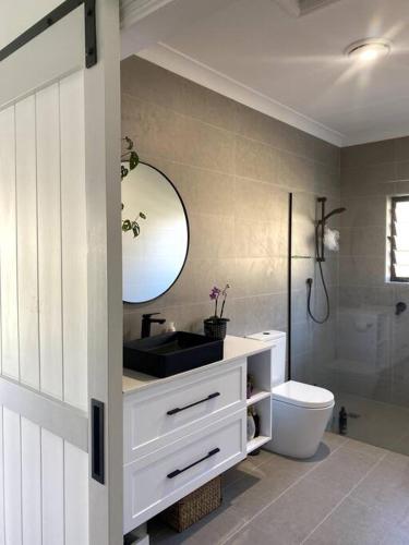 a bathroom with a sink and a toilet and a mirror at Tweed River Retreat in Tweed Heads