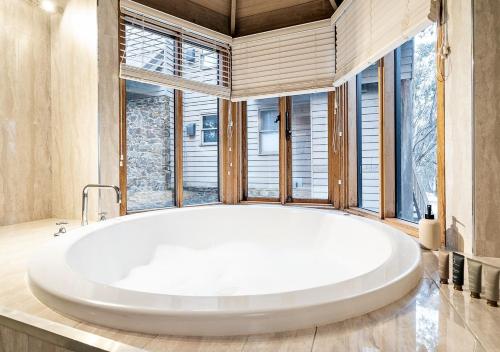 a large white tub in a bathroom with windows at Crystal Brook Lodge in Dinner Plain