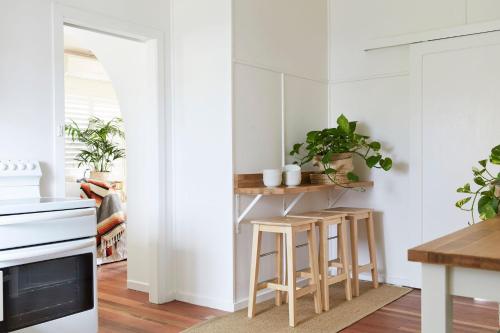 a kitchen with white walls and wooden stools at Bungalow105 in Byron Bay
