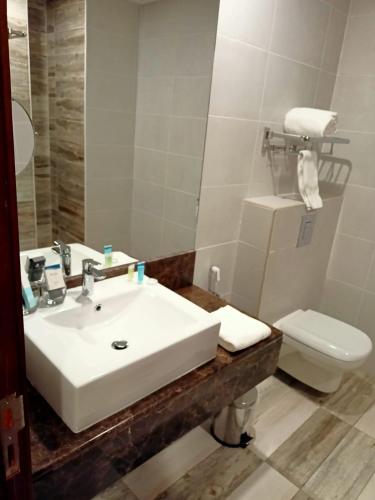 a bathroom with a white sink and a toilet at Grand Tourist Hotel in Muscat