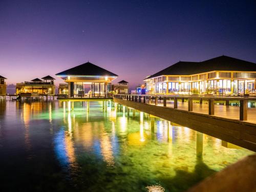 a group of buildings on the water at night at Angsana Velavaru In-Ocean Villas in Dhaalu Atoll