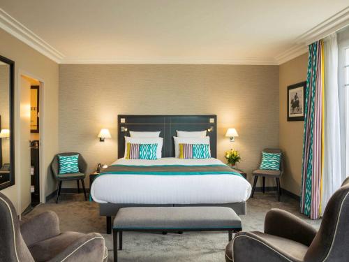 ラ・ボールにあるホテル メルキュール ラ ボール マジェスティックの大きなベッドと椅子2脚が備わるホテルルームです。