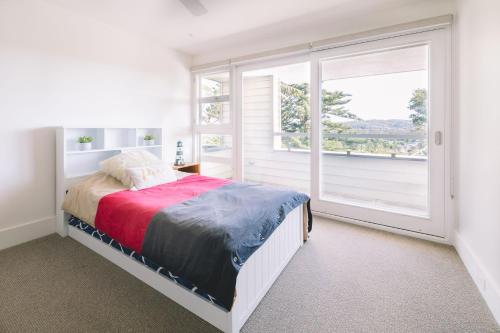ein Schlafzimmer mit einem Bett und einem großen Fenster in der Unterkunft Turimetta Beach House in Warriewood