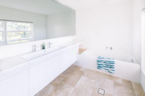 ein weißes Bad mit 2 Waschbecken und einem Fenster in der Unterkunft Turimetta Beach House in Warriewood