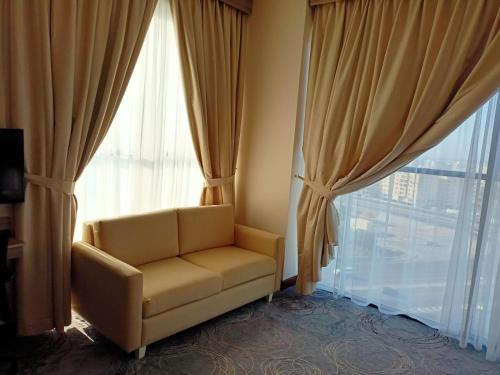 a living room with a couch and a large window at Grand Tourist Hotel in Muscat