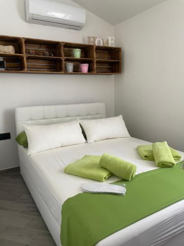 Una cama blanca con dos almohadas verdes. en Residence4a-Appartamento Verde, en Ravni