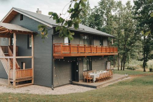 ein Haus mit einer Terrasse mit einem Tisch darauf in der Unterkunft Sniegi Apartments with sauna in Madona