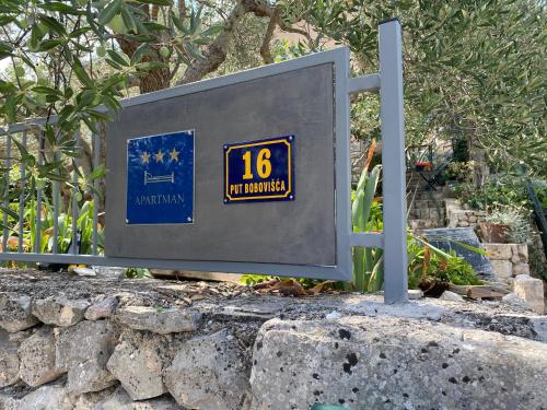 a sign sitting on top of a stone wall at Apartman Silna your new home with terrace and garden in Bobovišća