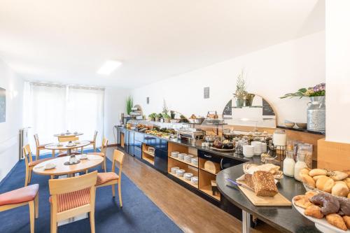 een ontbijtruimte met een buffet met brood en tafels bij acora Düsseldorf Living the City in Düsseldorf
