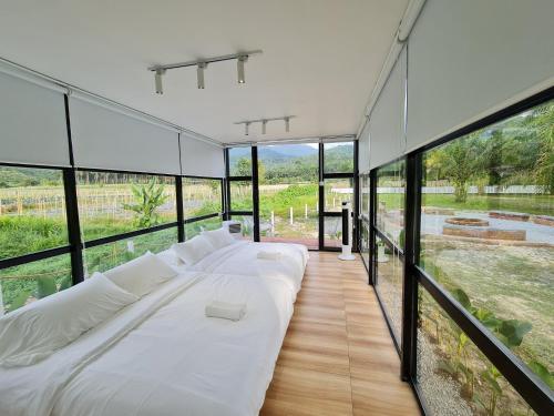 ein großes weißes Bett in einem Zimmer mit Glaswänden in der Unterkunft Holistay Forest Villa I 34 Pax I Gathering I Team Building I Wedding in Hulu Yam Baharu