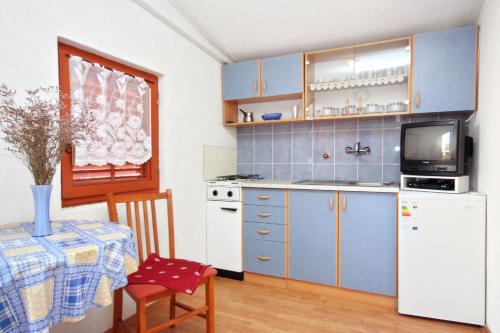 a kitchen with blue cabinets and a table with a tv at Apartments with a parking space Sabunike, Zadar - 5822 in Privlaka