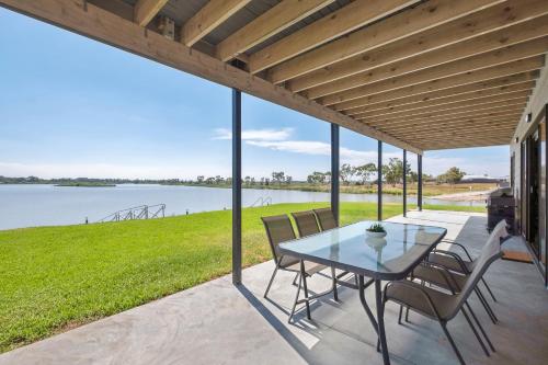 a patio with a table and chairs and a view of the water at 33 Jefferson Court, Wellington East in Wellington East
