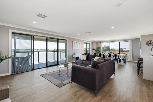 a living room with couches and tables and windows at 33 Jefferson Court, Wellington East in Wellington East