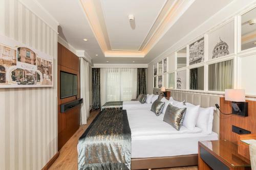 a hotel room with a white couch and a tv at Mukarnas Pera Hotel in Istanbul