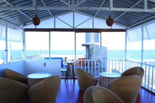 Habitación con sillas, mesas y vistas al océano. en Le Clarisse Guest House, en Pondicherry