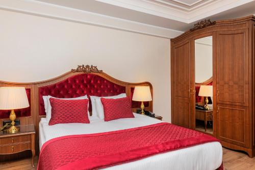 a bedroom with a large red bed with red pillows at Mukarnas Pera Hotel in Istanbul