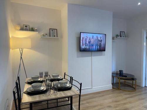 a dining room with a table and a television on the wall at Stylish and Modern 3 bed Apartment with FREE PARKING, in Newcastle upon Tyne