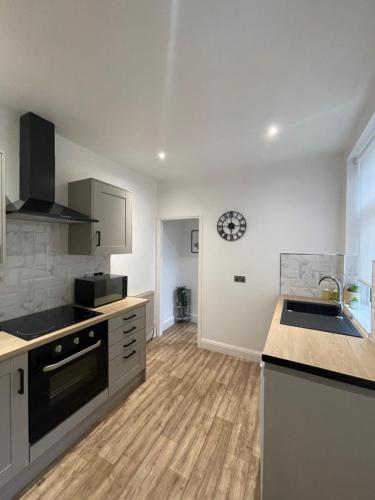 a kitchen with white cabinets and a wooden floor at Stylish and Modern 3 bed Apartment with FREE PARKING, in Newcastle upon Tyne