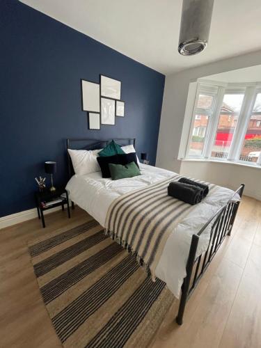 a bedroom with a large bed with blue walls at Stylish and Modern 3 bed Apartment with FREE PARKING, in Newcastle upon Tyne